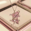 Pink butterfly pendant necklace on a reflective surface