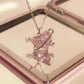 Pink butterfly pendant necklace on a reflective surface