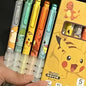 Set of colorful pens with cartoon character designs, including Pikachu, held next to their packaging.