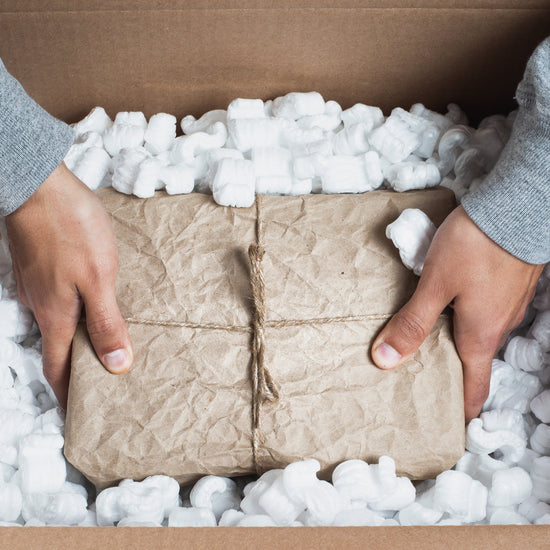Person packing cardboard boxes with bubble wrap in a cardboard box